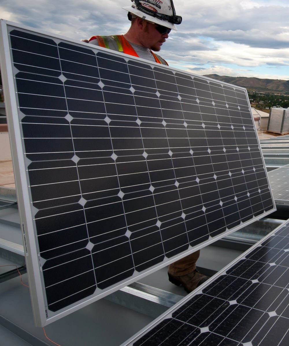 Instalador posicionando módulo fotovoltaico em cobertura metálica