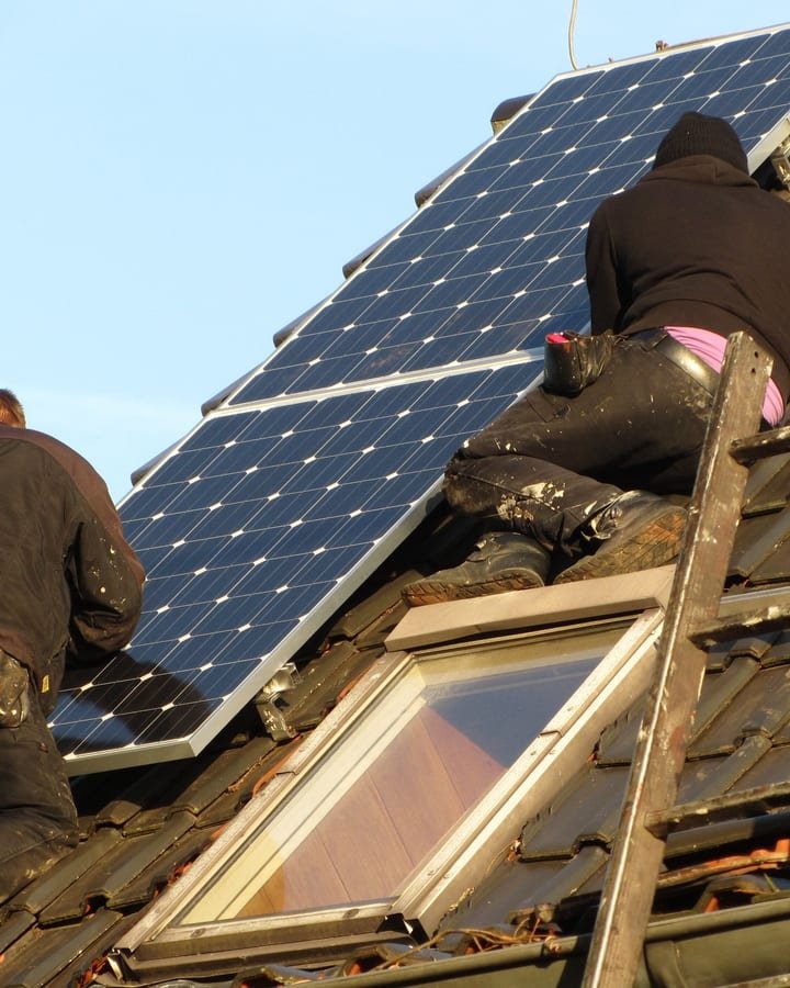 Instalador fixando módulos fotovoltaicos sobre telhado de telha cerâmica